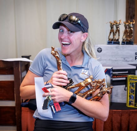 Abby Zeedyk of Merritt Contracting gathering her team's second place trophies at the 2026 IRMCA Fore Scholars Golf Outing.